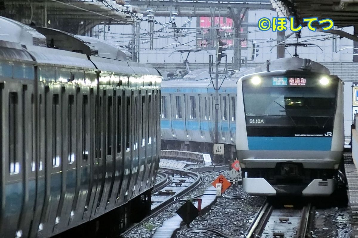 Two E233 series Keihin-Tohoku Line trains passing each other on Yamanote Line track at Ueno Station