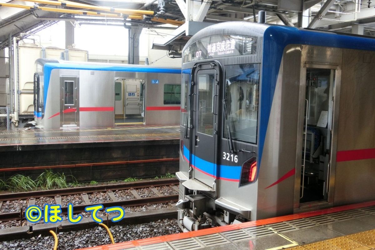 Keisei 3200 Series main line and Matsudo Line trains side by side at Keisei Tsudanuma Station